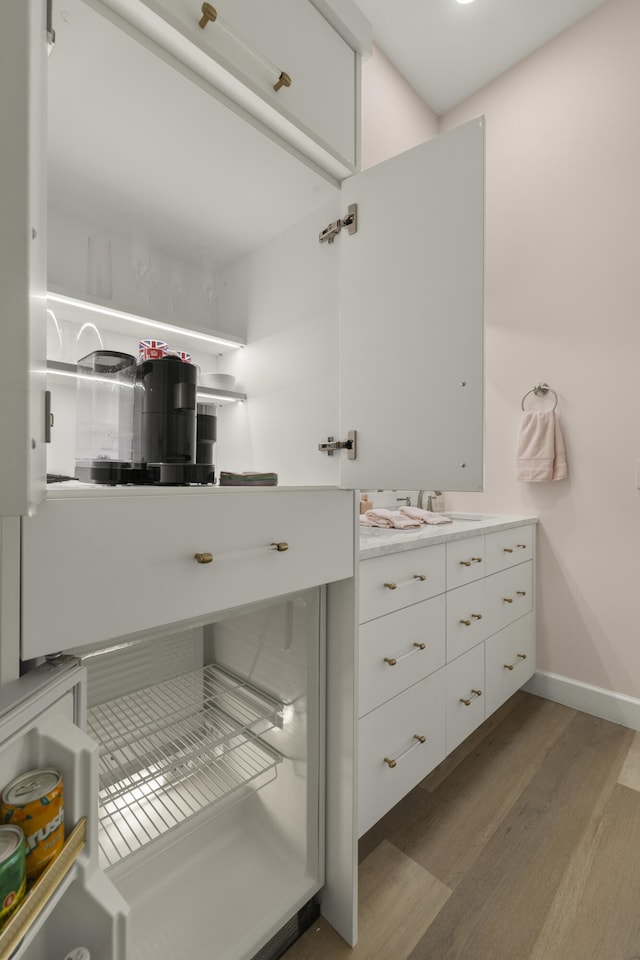 bathroom featuring baseboards, wood finished floors, and vanity