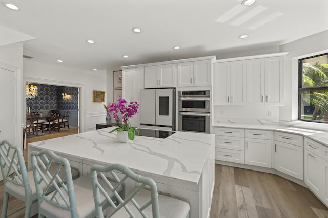 kitchen featuring stainless steel double oven, light wood-style flooring, refrigerator, and white cabinets