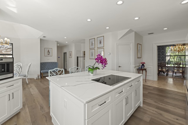 kitchen featuring a chandelier, light wood finished floors, white cabinetry, and black electric stovetop