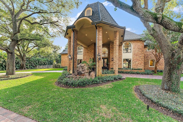 view of front of home featuring a front yard, fence, brick siding, and driveway