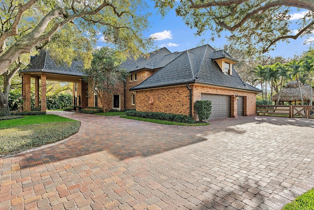 view of front of house featuring a gate, decorative driveway, a high end roof, fence, and brick siding