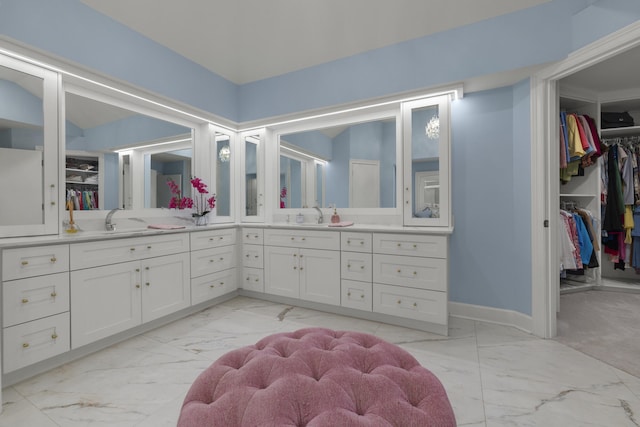 bathroom featuring marble finish floor, vanity, a walk in closet, and baseboards