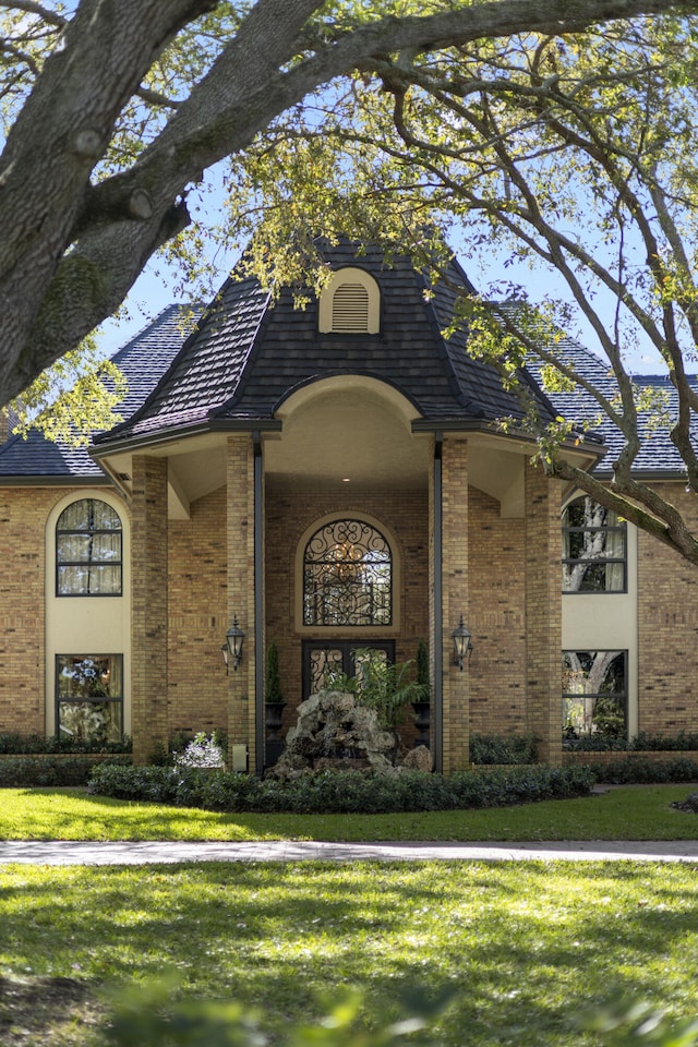 view of front of house featuring brick siding and a yard