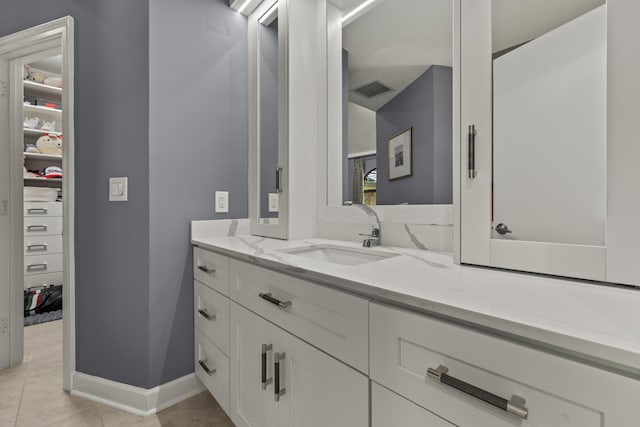 bathroom with vanity, baseboards, visible vents, a spacious closet, and tile patterned floors