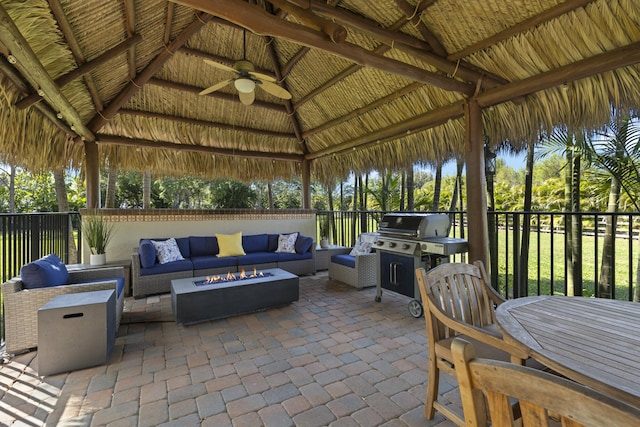 view of patio featuring area for grilling, a ceiling fan, fence, a gazebo, and an outdoor living space with a fire pit