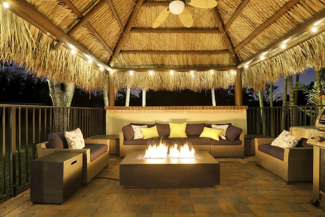 patio at night with a gazebo, a ceiling fan, and an outdoor living space