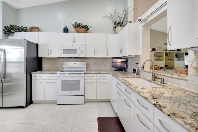 kitchen featuring white appliances, light tile patterned floors, a sink, white cabinetry, and tasteful backsplash