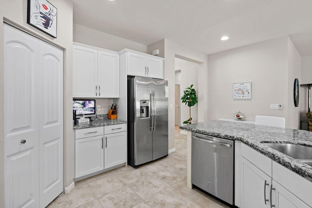 kitchen featuring light tile patterned floors, sink, white cabinetry, stainless steel appliances, and light stone countertops