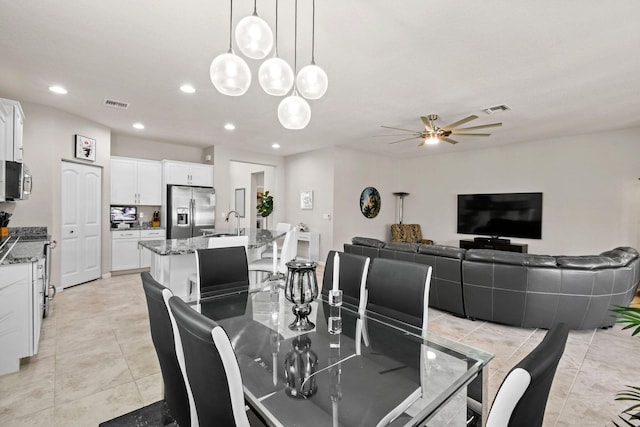 dining area featuring sink, light tile patterned floors, and ceiling fan