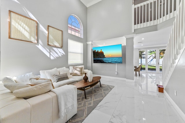 living area with marble finish floor, decorative columns, a towering ceiling, and baseboards