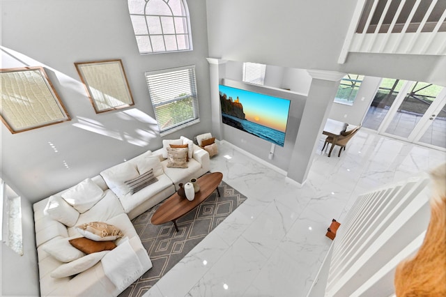 living area featuring a towering ceiling, marble finish floor, and baseboards