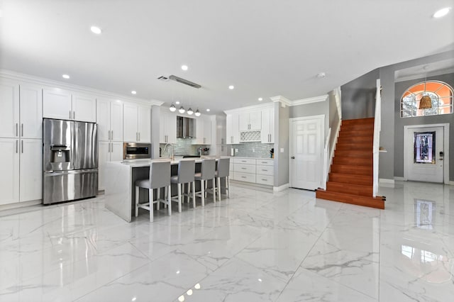 kitchen with appliances with stainless steel finishes, a kitchen island with sink, white cabinets, and light countertops