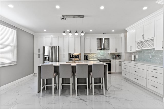 kitchen with a center island with sink, white cabinets, wall chimney exhaust hood, stainless steel appliances, and light countertops