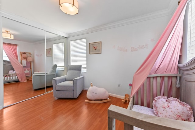 bedroom with hardwood / wood-style floors, a wall mounted air conditioner, ornamental molding, and a closet