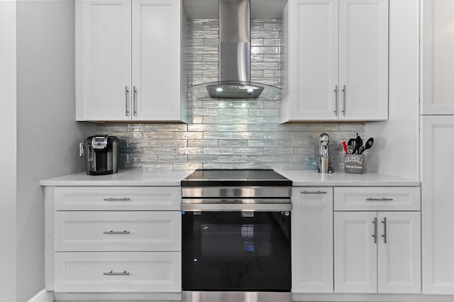 kitchen featuring light countertops, electric range, wall chimney exhaust hood, and white cabinetry