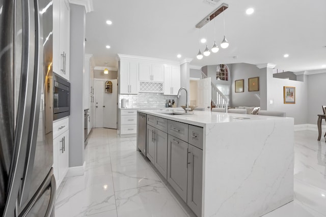 kitchen with appliances with stainless steel finishes, white cabinetry, sink, crown molding, and light stone countertops