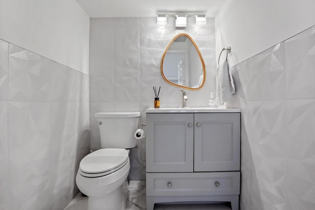 half bath featuring tile walls, vanity, and toilet