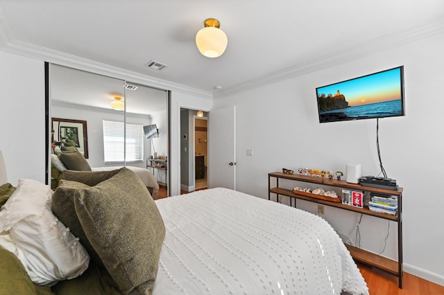 bedroom with crown molding, wood-type flooring, and a closet