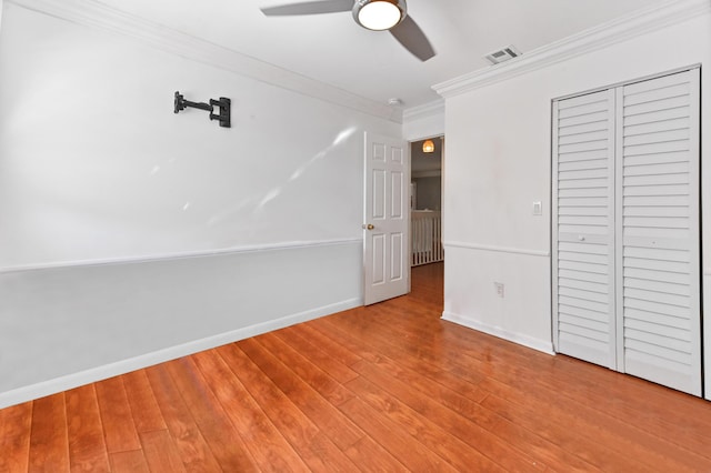 unfurnished bedroom featuring a closet, ornamental molding, light hardwood / wood-style floors, and ceiling fan