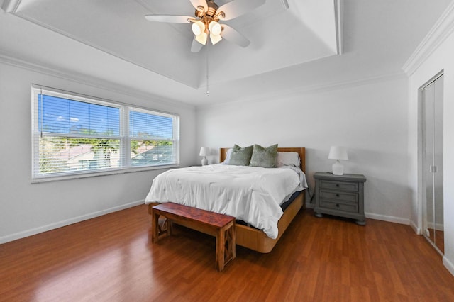 bedroom with crown molding, wood-type flooring, a raised ceiling, and ceiling fan