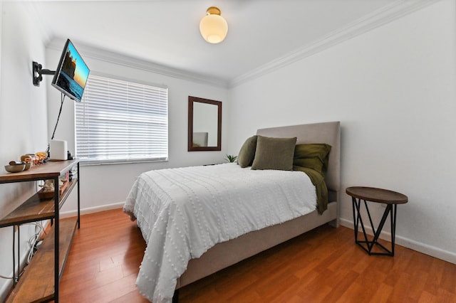 bedroom featuring ornamental molding, wood finished floors, and baseboards