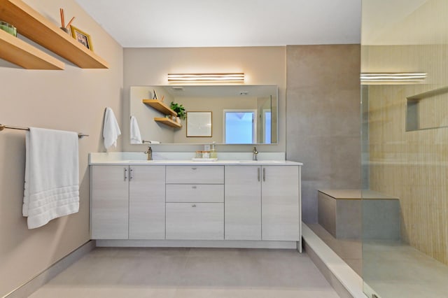 full bathroom with double vanity, walk in shower, and a sink