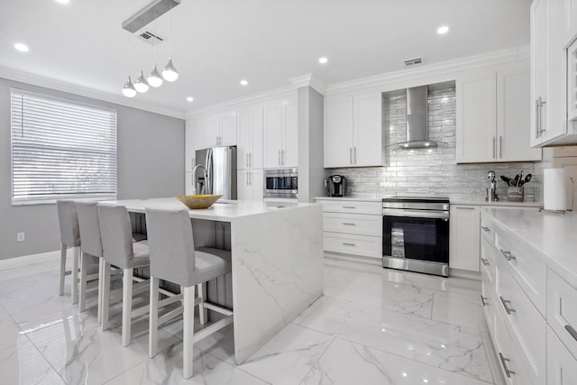 kitchen featuring appliances with stainless steel finishes, white cabinetry, an island with sink, and wall chimney exhaust hood