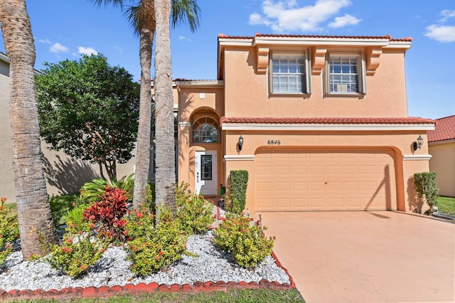 mediterranean / spanish home with an attached garage, a tiled roof, concrete driveway, and stucco siding