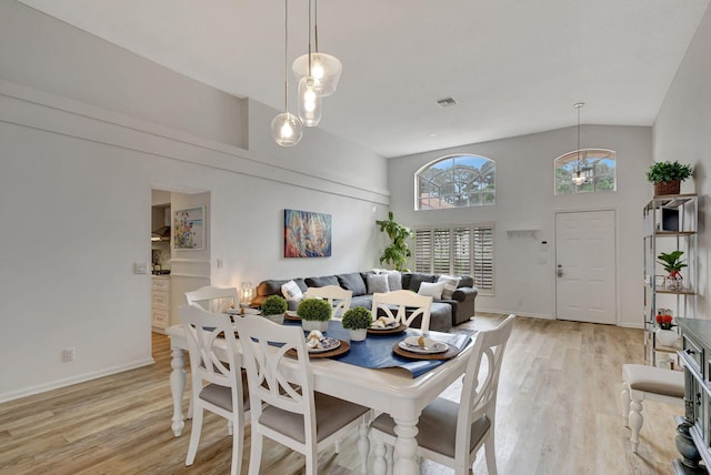 dining space featuring high vaulted ceiling, light hardwood / wood-style flooring, and a wealth of natural light