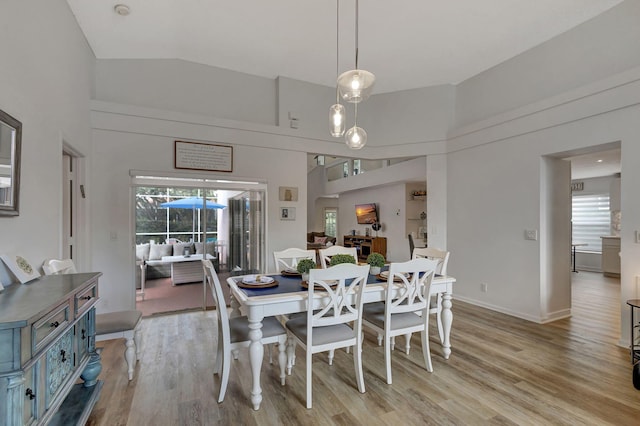 dining area with light wood-type flooring, a wealth of natural light, and high vaulted ceiling