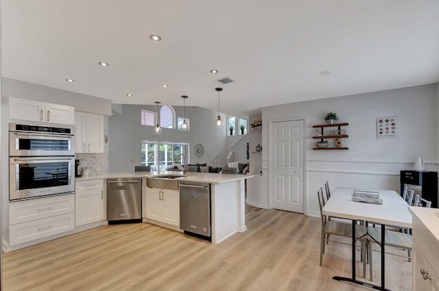 kitchen featuring pendant lighting, light hardwood / wood-style flooring, stainless steel appliances, and white cabinets