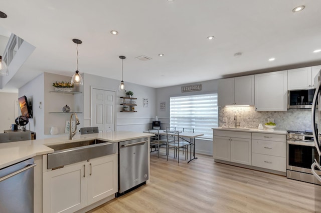 kitchen featuring stainless steel appliances, white cabinetry, sink, and pendant lighting