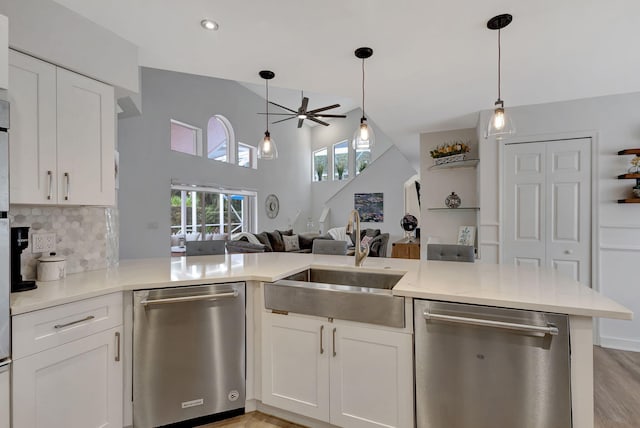 kitchen featuring white cabinetry, stainless steel dishwasher, kitchen peninsula, and pendant lighting