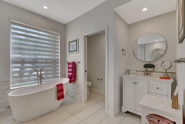 bathroom featuring vanity, a healthy amount of sunlight, a bathtub, and toilet