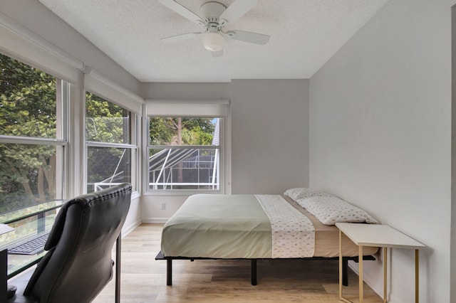 bedroom with multiple windows, a textured ceiling, light hardwood / wood-style floors, and ceiling fan