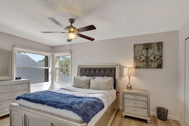 bedroom with ceiling fan, light hardwood / wood-style flooring, and a textured ceiling