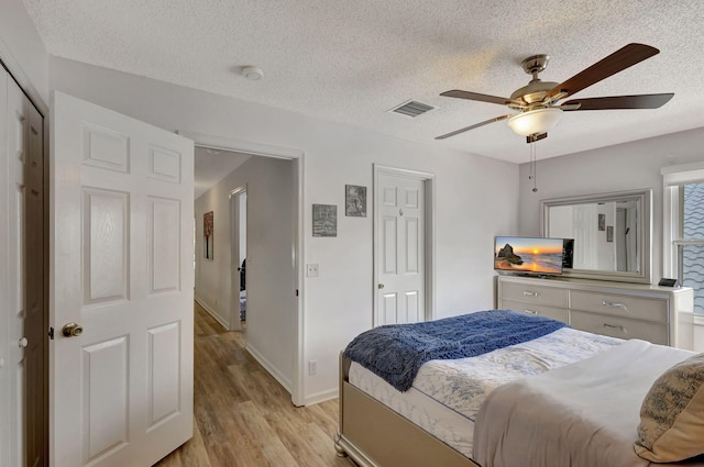 bedroom with ceiling fan, a closet, a textured ceiling, and light wood-type flooring