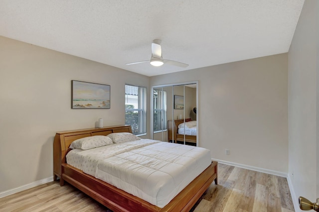 bedroom featuring ceiling fan, a closet, light hardwood / wood-style flooring, and a textured ceiling