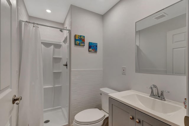 bathroom featuring walk in shower, tile walls, vanity, and toilet