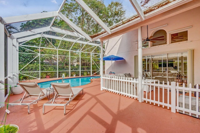 view of swimming pool featuring ceiling fan, a lanai, and a patio area