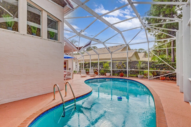 view of swimming pool featuring glass enclosure and a patio area