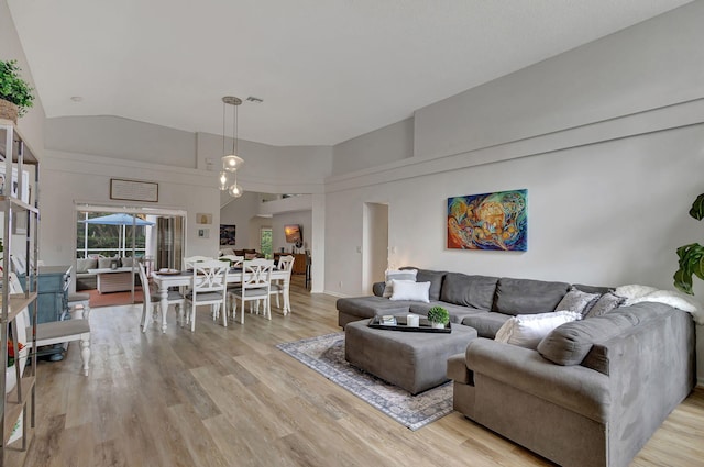 living room with high vaulted ceiling and light wood-type flooring