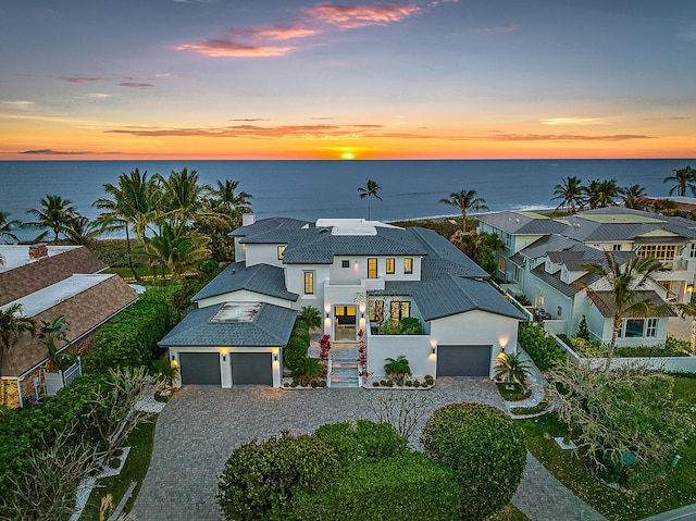 view of front of house with a garage, a water view, and solar panels