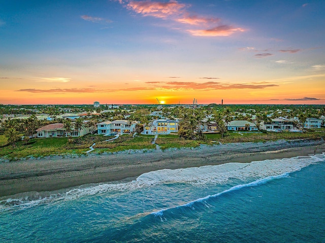 aerial view at dusk with a beach view and a water view