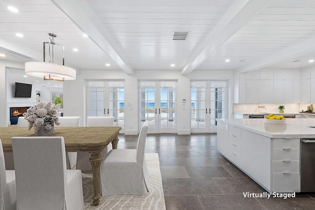 kitchen with decorative light fixtures, beamed ceiling, white cabinets, light stone countertops, and french doors