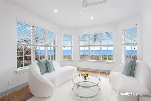 living area with a wealth of natural light, wood-type flooring, and a water view