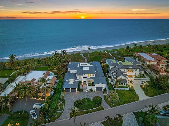 aerial view at dusk with a water view and a view of the beach