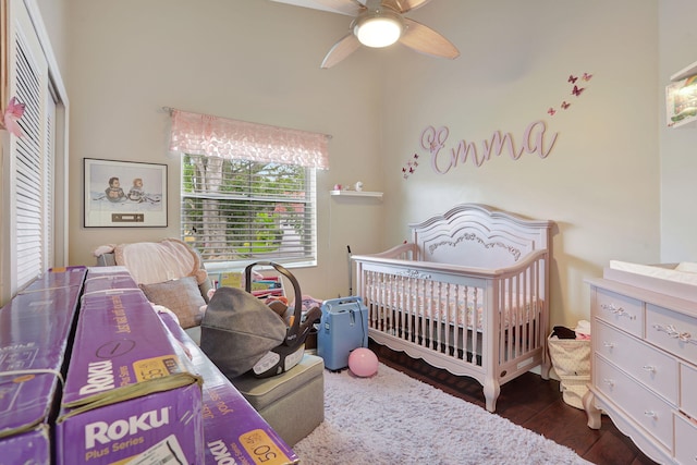 bedroom featuring dark wood-type flooring, a crib, a closet, and ceiling fan