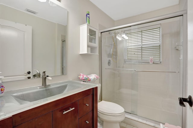 bathroom featuring vanity, a shower with shower door, and toilet