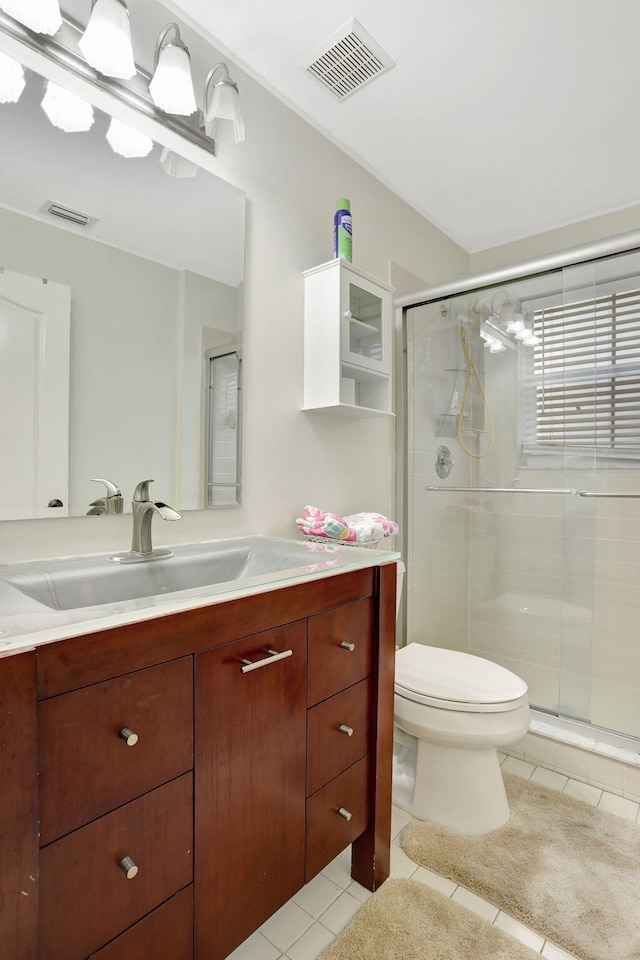 bathroom featuring walk in shower, vanity, toilet, and tile patterned flooring